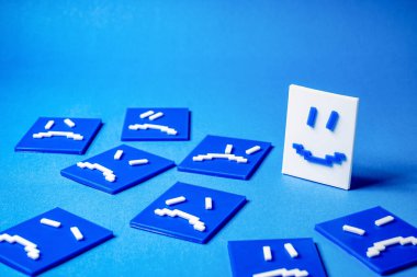 Üzgün ve kızgın yüzler etrafında mutlu bir yüz kavramı.