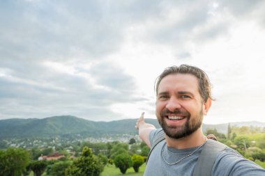 Yaz tatilinde gün doğumunda fotoğraf çeken yakışıklı bir adam. Dışarıda kameraya gülümseyen sırt çantalı mutlu bir yürüyüşçü. Parkta yürüyen bir turist..