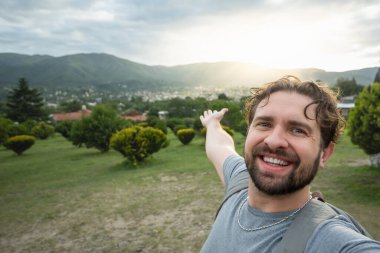 Genç yürüyüşçü bir bakış açısıyla selfie portresi çekiyor. Kameraya gülümseyen mutlu adam. Yürüyüş, spor, seyahat ve teknoloji konsepti. Parlak filtre.