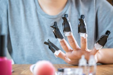 Yarı kalıcı tırnak cilasını sökmek için kadın eli. Genç bayan boya çıkarıcının harekete geçmesini bekliyor..