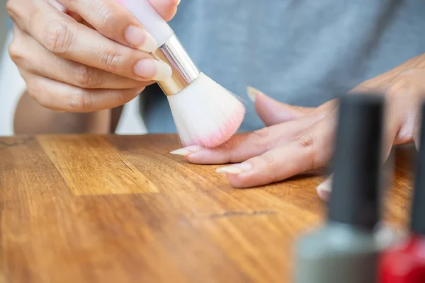 Woman cleaning her nails after filing the top before applying semi-permanent nail polish.