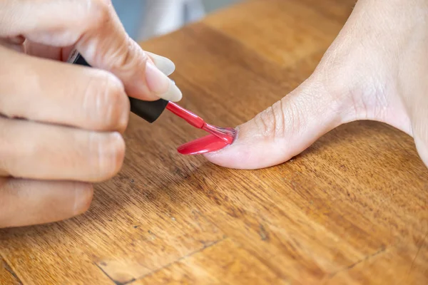 Woman painting her big finger with a semi-permanent nail polish.