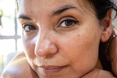 Göz kapaklarında kalıcı makyaj olan doğal Latin bir kadının çok yakın bir fotoğrafı..