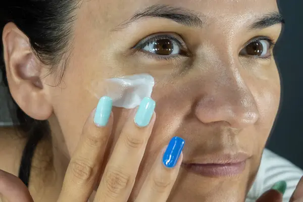 Latin kadın, yüz kremi ve refah için cilt bakımı. Deri parıltısı ve güneş kremi. Kolajen ve dermatoloji kozmetik losyonu. Doğal kozmetik tedavisi. Aynanın önündeki kadın..