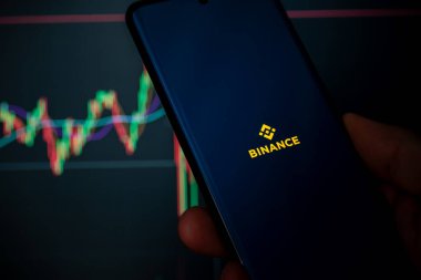 Cordoba Eyaleti, Arjantin - 11 Mart 2024: Binance mobil uygulaması telefonla çalışıyor. Arka planda kripto para birimi işlemleri görülebilir.