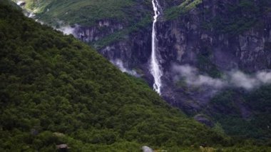 Norveç 'in bulutlu tepeleri ve yeşil çam ormanlarıyla çevrili Norveç dağlarında çağlayan şelaleler. Dramatik Norveç manzarası. Yüksek kalite 4k görüntü.