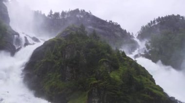 Lefossen Şelalesi bulutlu, yağmurlu bir günde, Norveç 'te yeşil çam ormanlarıyla çevrili. Su kanyonlarda akıyor ve kasvetli bir günde sis yaratıyor. Yüksek kalite 4k görüntü