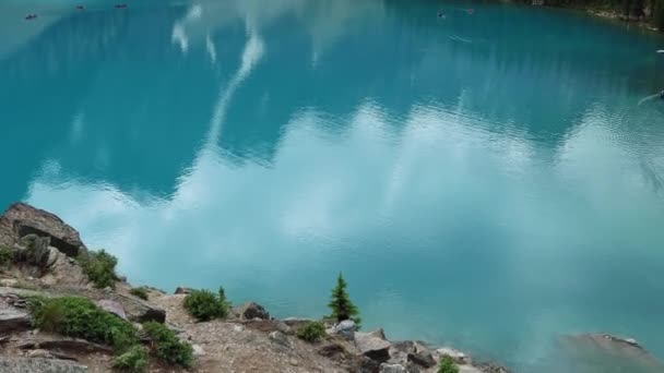 加拿大艾伯塔省班夫国家公园 我们俯瞰着高耸的锯齿状山脉和茂密的松树林的莫兰湖中明亮的蓝色冰川水 独木舟在湖上 高质量的4K镜头 — 图库视频影像