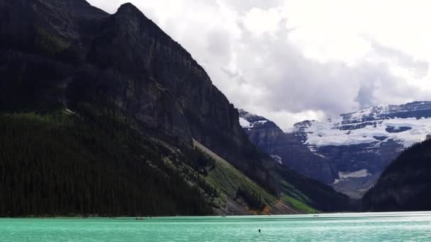 曇った日にルイーズ湖の明るい青い氷河水 バンフ国立公園 アルバータ カナダ 高い山々 濃い松林に囲まれた湖 高品質の4K映像 — ストック動画