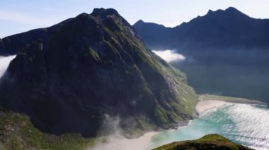 Uzun sivri dağlar, kristal berrak mavi su ve Norveç 'in Lofoten Adaları' ndaki Kvalvika Sahili 'nin beyaz kumlu plajları. Kuzey Kutbu 'ndaki plaj. Yüksek kalite 4k görüntü