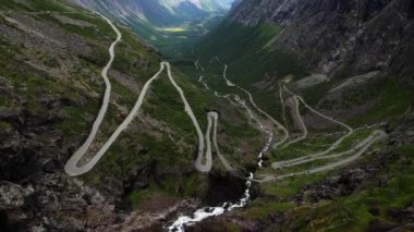 Trollerin yolu dağdan aşağıya ve vadiden aşağıya doğru kıvrılıyor. Bulutlu bir günde, Norveç 'in her iki tarafında da yüksek dağlar yükseliyor. Huysuz Norveç manzarası. Yüksek kalite 4k görüntü