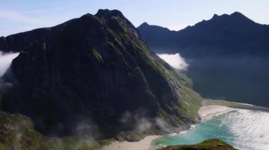 Uzun sivri dağlar, kristal berrak mavi su ve Norveç 'in Lofoten Adaları' ndaki Kvalvika Sahili 'nin beyaz kumlu plajları. Kuzey Kutbu 'ndaki plaj. Yüksek kalite 4k görüntü