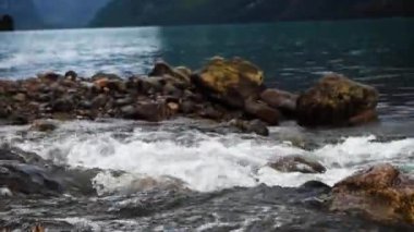 Norveç 'in parlak mavi buzul gölü üzerinde yükselen bulutlarla çevrili Lovatnet vadisinin uzun Norveç dağları. Sisli bir günde atmosferik manzara. Yüksek kalite 4k görüntü.