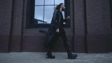 Siyah deri ceketli adam duvarda yürüyor, Gotik tarzında.