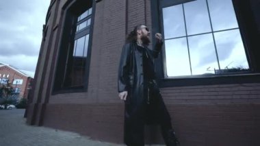 Siyah deri ceketli adam duvarda yürüyor, Gotik tarzında.