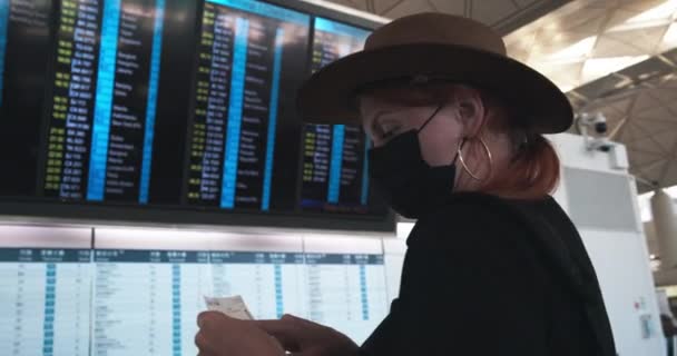Дівчина Масці Капелюх Виглядає Відривній Дошці Аеропорту — стокове відео