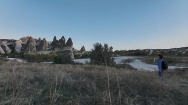 Kapadokya 'nın kayalıkları arasında gezen Sırt çantalı ve Şapkalı Gezgin Kız,