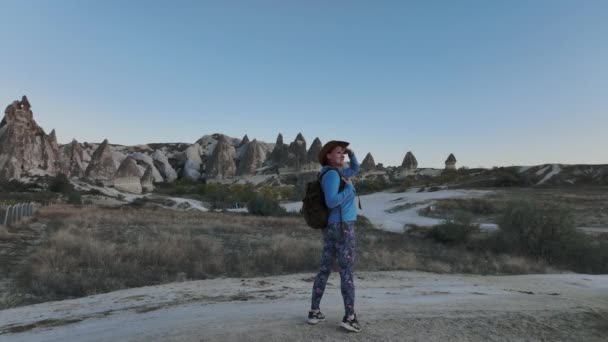 在卡帕多西亚的岩石和空中景观中 带着背包和帽子的旅行女孩 — 图库视频影像