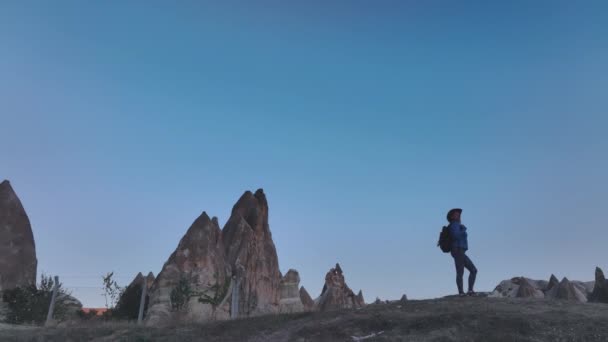 在卡帕多西亚的岩石和空中景观中 带着背包和帽子的旅行女孩 — 图库视频影像