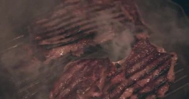 Izgarada kızartılmış dumanlı büyük et bifteği.