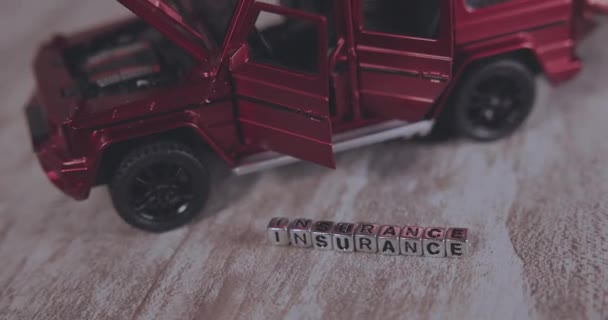 Ubezpieczenie Napis Kostkach Pobliżu Czerwonego Samochodu Miniatura — Wideo stockowe