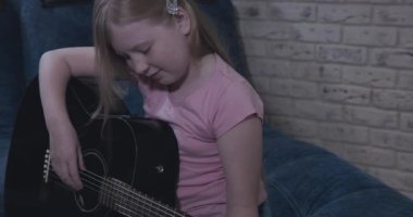 Zeki genç kız siyah gitar çalmayı öğreniyor.
