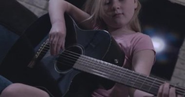 Zeki genç kız siyah gitar çalmayı öğreniyor.