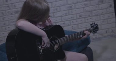 Zeki genç kız siyah gitar çalmayı öğreniyor.