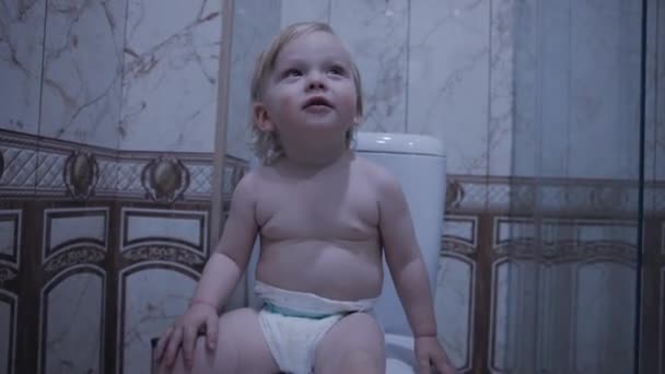 宝宝正坐在马桶上拿着卫生纸 — 图库视频影像