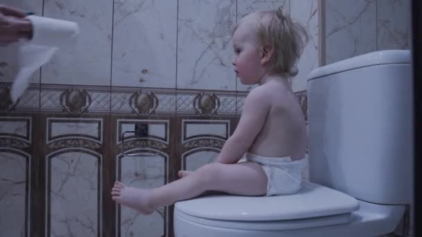 宝宝正坐在马桶上拿着卫生纸 — 图库视频影像