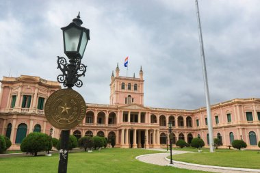 Asuncion 'daki hükümet sarayı, bulutlu bir gökyüzünün altında, manikürlü bahçeler arasında mimari güzelliğini sergileyerek görkemli bir şekilde ayakta duruyor..