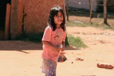 Asuncion, Paraguay - 21 Ağustos 2023: Paraguay 'ın kırsal kesimlerinde, açık pembe gömlek ve renkli pantolon giymiş, uzun siyah saçlı, gülümseyen genç bir kız..