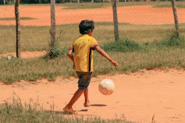 Asuncion, Paraguay - 21 Ağustos 2023: Güneşli bir öğleden sonra, genç bir çocuk Paraguay 'da bir futbol topunu tekmeliyor..