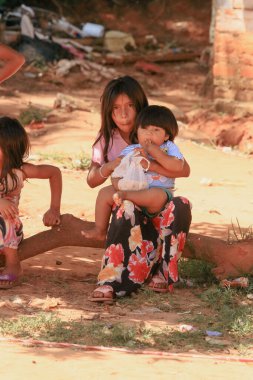 Asuncion, Paraguay - 21 Ağustos 2023: Paraguay 'ın kırsal kesimlerinde, çocuklar bir kütüğün üzerinde otururken neşeli aktiviteler yaparlar, yakın bağlarını ve kaygısız çocukluklarını vurgularlar..