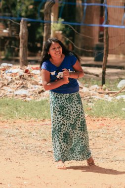 Asuncion, Paraguay - 21 Ağustos 2023: Paraguay 'da neşeli gülüşü renkli bir kıyafet içinde güneşli bir öğleden sonrayı aydınlatan genç bir kız eğleniyor. Çocuklar yakınlarda oynarken görülürler..