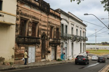 Bir adam Asuncion, Paraguay 'da tarihi binalarla dolu cadde boyunca yürüyor. Hava bulutlu, nehir kıyısında sakin bir ortam sağlıyor..