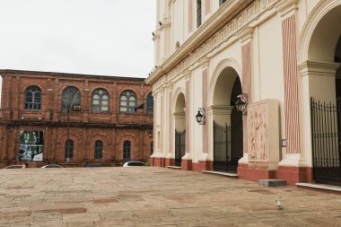 Asuncion, Paraguay 'ın canlı mimarisi, bulutlu gökyüzünün altında güzel bir plazanın yer aldığı tarihi binalar ve modern dokunuşların bir karışımını sergiliyor..