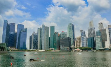 Singapur 'un çarpıcı silueti, sudaki yansımalarla berrak bir gökyüzüne karşı modern mimariyi sergiliyor..