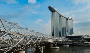 Gece Singapur 'un üzerine çökerken parlayan Marina Körfezi Kumları kulesi sarmal köprünün üzerinde yükseliyor ve modern mimarisini gökyüzüne vurguluyor..