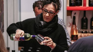 Alba, İtalya - 27 Ekim 2024: İtalya 'da düzenlenen Alba Yer Mantarı Festivali sırasında bir kadın bardağa şarap dökerken, ziyaretçiler yerel trüf mantarları ve mutfak tatları deniyorlar..