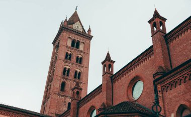 Etkileyici tuğla çan kulesi Alba, İtalya 'da solgun bir gökyüzüne karşı duruyor. Şehrin zengin tarihini ve ortaçağ köklerine benzeyen çarpıcı mimari özelliklerini vurguluyor..