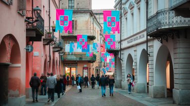 Alba, İtalya - 27 Ekim 2024: Alba, İtalya sokaklarını süsleyen renkli pankartlar, insanların akşamları kutlamaların keyfini çıkardıkları bir yer. Atmosfer hareketli, yerliler toplanıyor ve büyüleyici kasabayı keşfediyorlar..