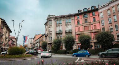 Alba, İtalya - 27 Ekim 2024: Albas pitoresk caddeleri, arabalarla dolup taşan ve renkli afişlerle süslenen tarihi ve modern mimari bir karışım sergileyerek, gün içinde canlı bir kentsel atmosfer yaratıyor.