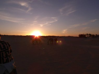 Çölde at süren bir grup insan.