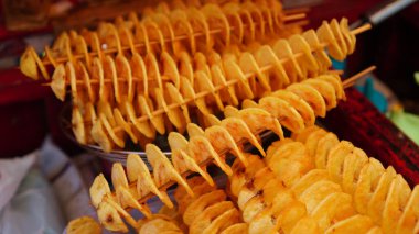 Uzun bir bambu şiş üzerinde sarımsı şekilli kızarmış patates, üstüne de sos. Genellikle baharatlı sosla yenir..