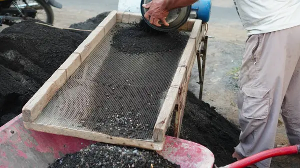 Kablo ve ahşap filtreler kullanarak iyi kalite malzeme elde etmek için kumu elle filtreleme süreci.