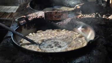 Geleneksel ahşap kaplı bir mutfakta büyük bir tavada tofu kızartıyorum..
