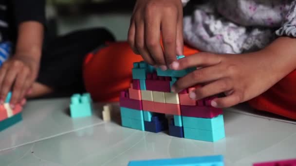 子供は床にプラスチックのおもちゃのブロックを組み立てて遊びます — ストック動画