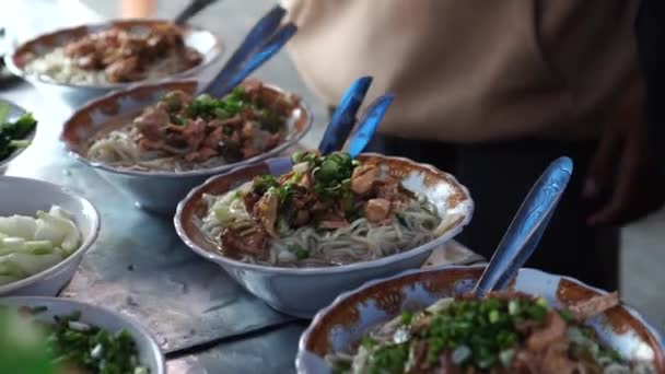 一个摊贩在街上的食品店里正在几个碗里准备鸡肉和蔬菜面 — 图库视频影像