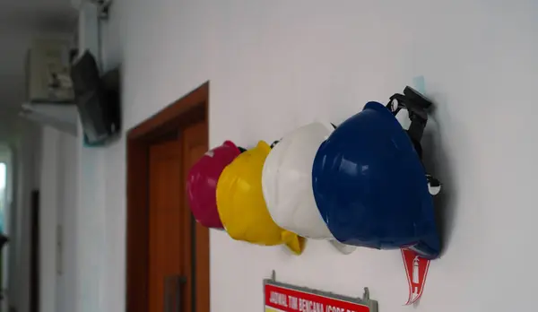 safety helmets on the wall of the room, hanging in a row in different colors